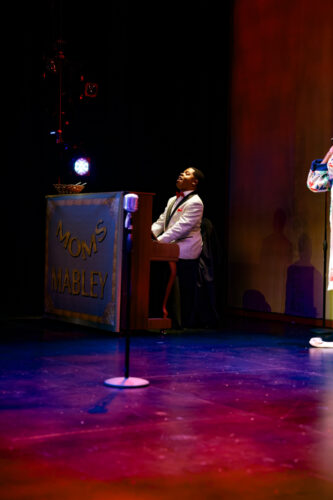 Man at a piano in M Ensemble's "Moms Mabley."